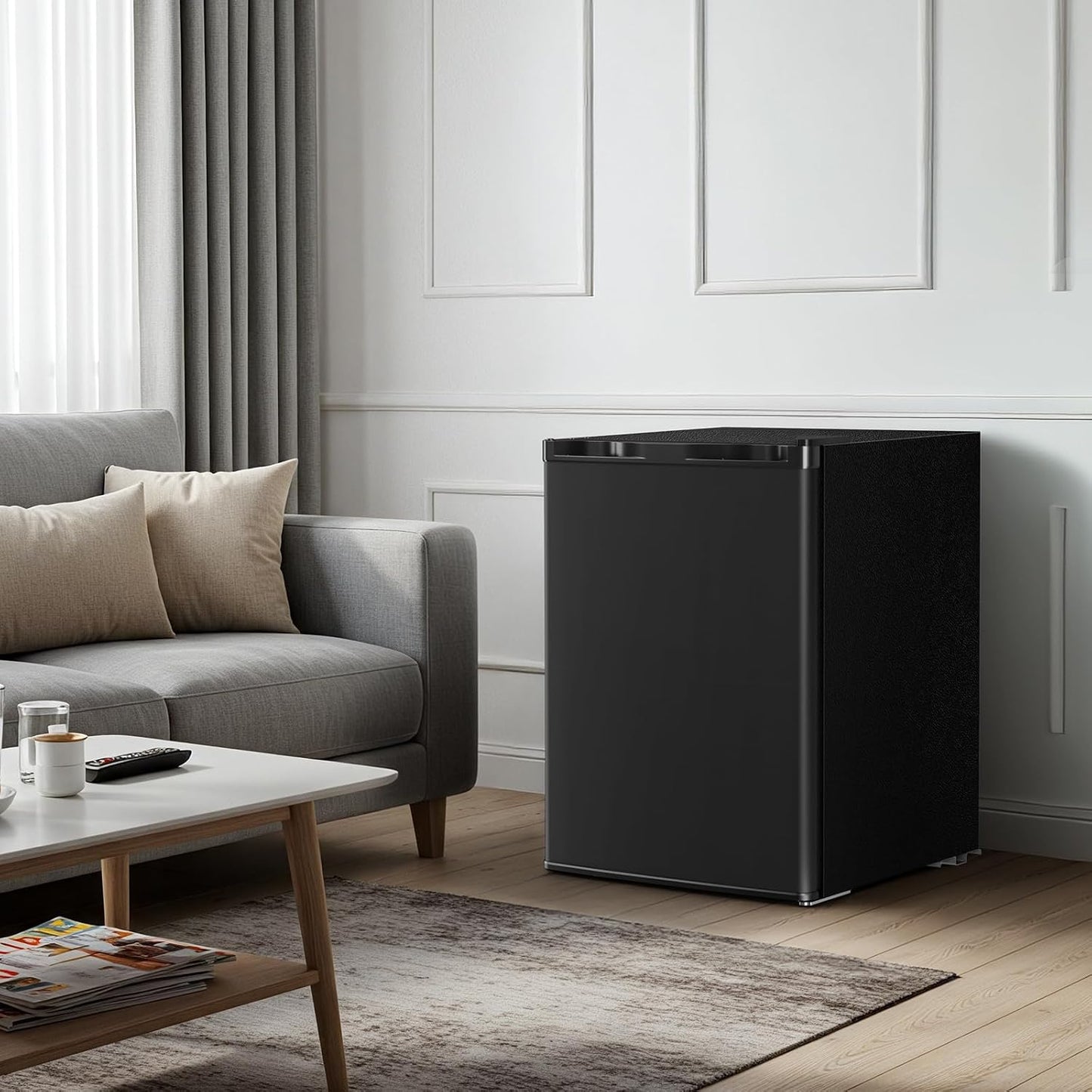 Black refrigerator in a living room with a gray sofa and wooden coffee table.